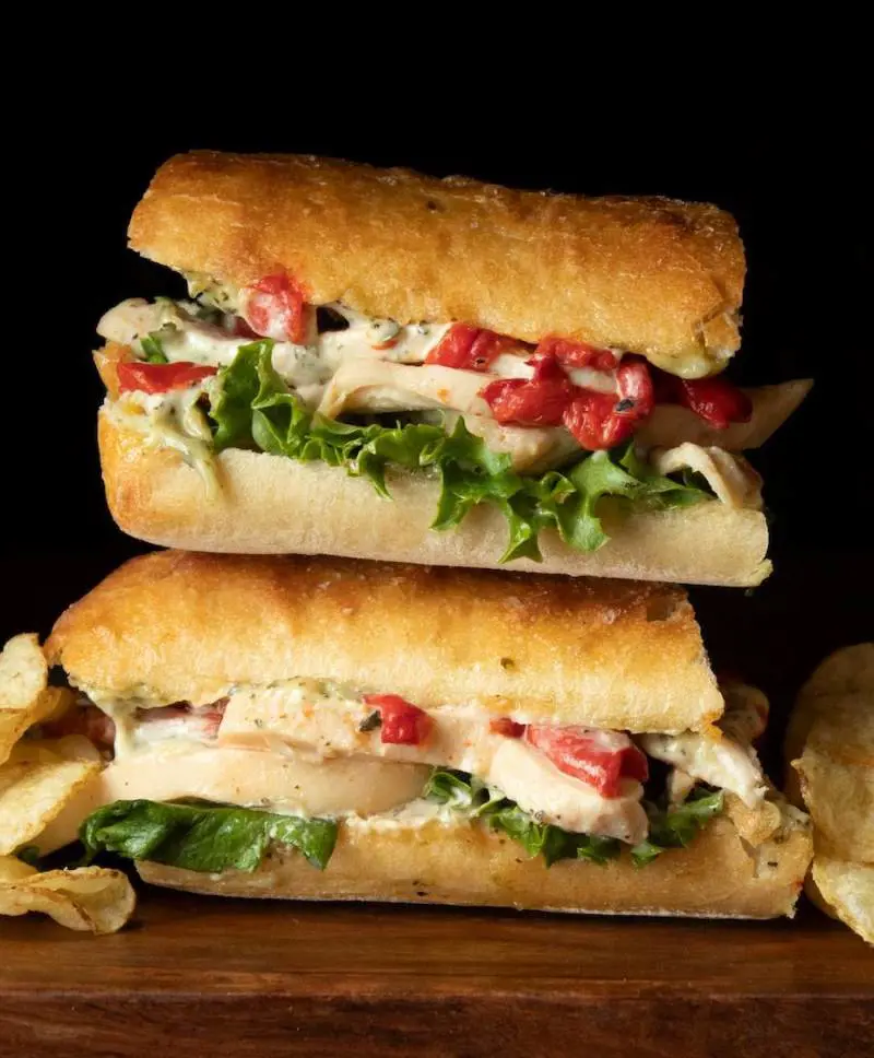 Chicken Pesto Sandwich featuring grilled chicken, pesto mayonnaise, roasted red peppers, and lettuce on focaccia bread